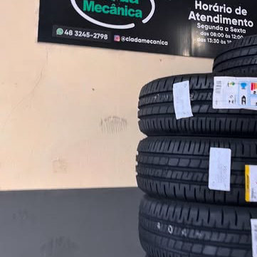 Pilha de pneus novos com etiqueta embaixo da placa de horário de atendimento