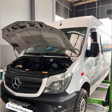 Van Mercedes Sprinter branca com o capô aberto dentro da oficina